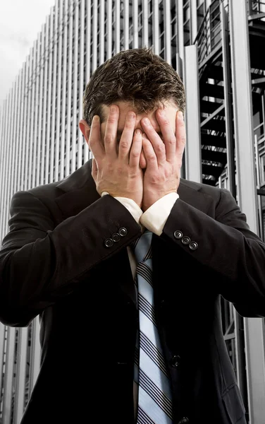 Бизнесмен покрывает лицо отчаянно перед офисным зданием бизнес-района — стоковое фото