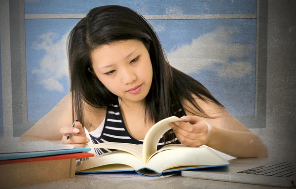 Pretty chinese asian young girl reading and studying with school books and computer laptop at home studio desk — Stockfoto