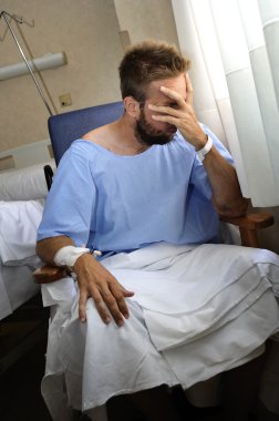 young injured man crying in hospital room sitting alone crying in pain worried for his health condition