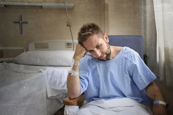 Young injured man in hospital room sitting alone in pain worried for his health condition — Stock Photo, Image