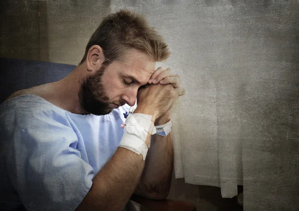 Young injured man in hospital room sitting alone in pain worried for his health condition — Stock Photo, Image