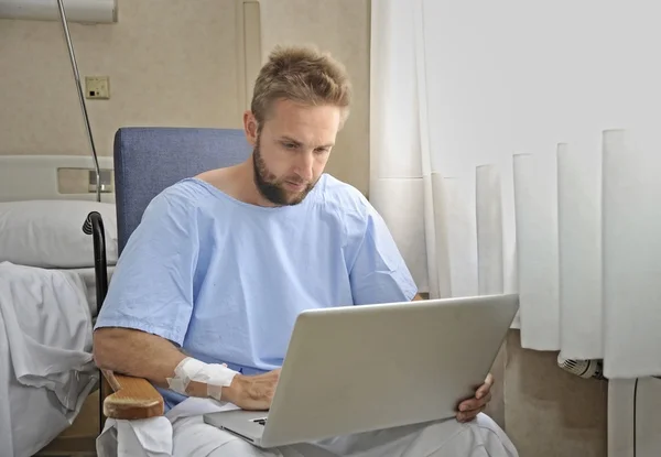 Hombre joven en la habitación del hospital usando internet investigando información sobre su propia enfermedad o lesión —  Fotos de Stock