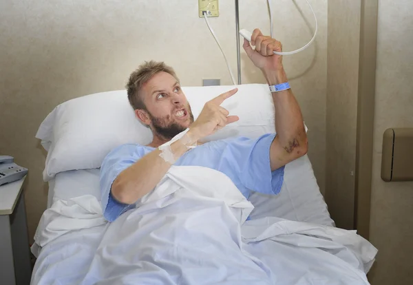 Hombre paciente enojado en la habitación del hospital acostado en la cama presionando el botón de llamada enfermera sentirse nervioso y molesto — Foto de Stock