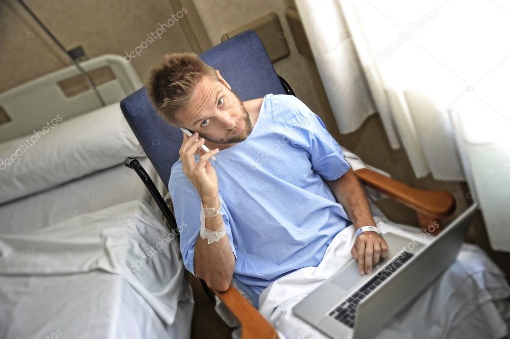 young workaholic business man in hospital room sick and injured after accident working with mobile phone and computer laptop