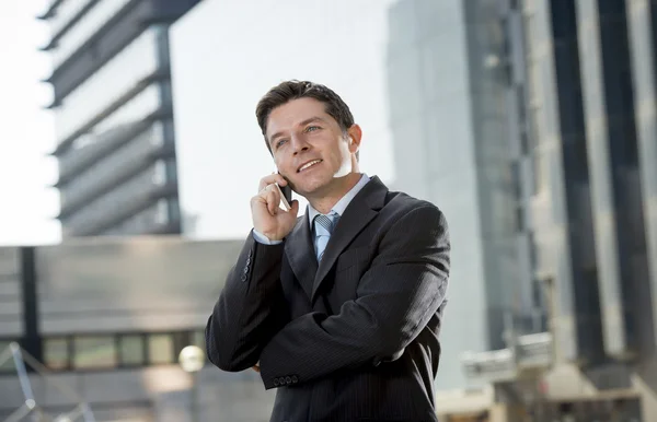 Joven atractivo hombre de negocios en traje y corbata hablando por teléfono móvil feliz al aire libre — Foto de Stock