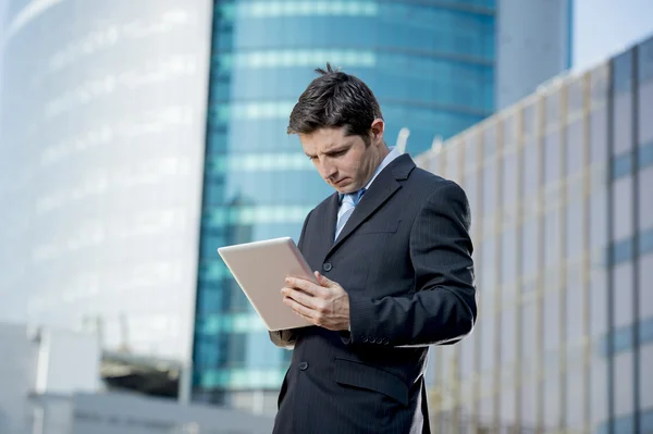 Бизнесмен держит цифровой планшет стоя на открытом воздухе рабочий деловой район — стоковое фото