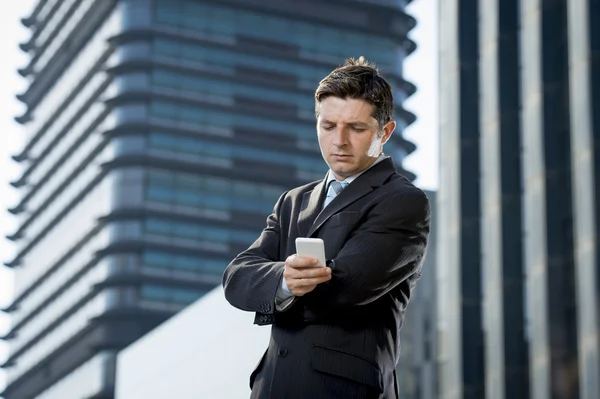 Unga attraktiva affärsman i kostym och slips ser textmeddelande på mobiltelefonen utomhus — Stockfoto