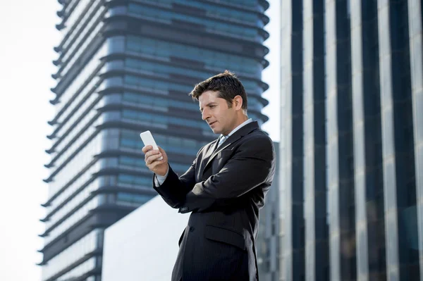 Joven atractivo hombre de negocios en traje y corbata buscando mensaje de texto en el teléfono móvil al aire libre — Foto de Stock