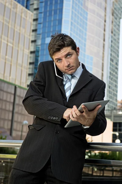 Busy businessman holding digital tablet and mobile phone overworked outdoors — Stock Photo, Image