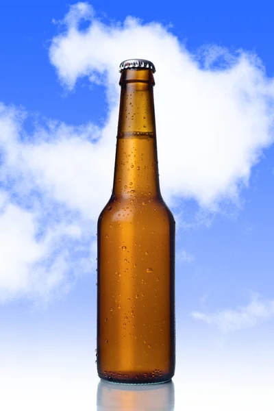 Golden beer with frost bubbles in brown glass bottle isolated on blue sky — Stock Photo, Image