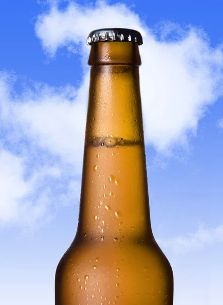 Macro beer golden bottle neck with frost and bubbles in brown glass isolated on blue sky — Stock Photo, Image