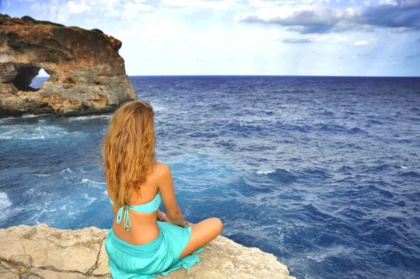 Young attractive woman looking at sea horizon sitting alone on r — Stock fotografie