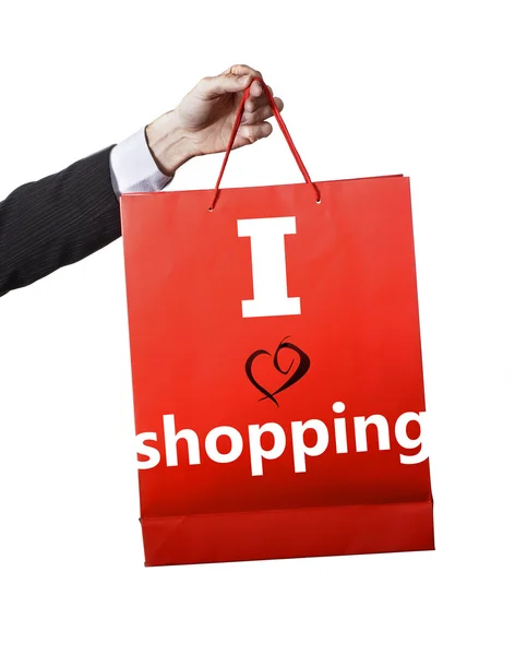 Uomo mano portando e mostrando una borsa rossa isolata su sfondo bianco I love Shopping motto — Foto Stock