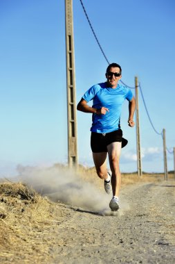 sport man with sun glasses running on countryside track with power line poles