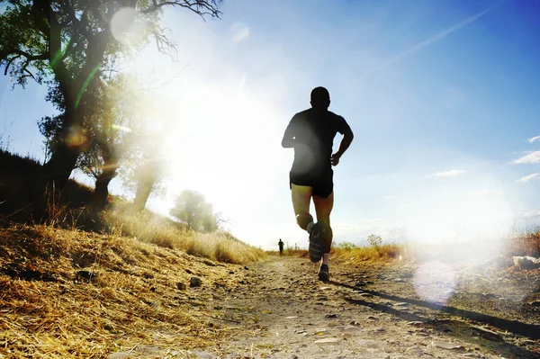 Силует молодого спортивного чоловіка, що біжить з перехресного змагання на літньому заході сонця — стокове фото