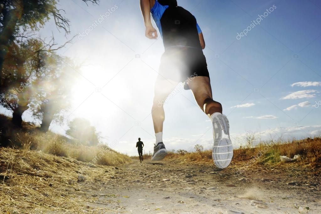 Silhouette of young sport man running off road cross country competition at summer sunset