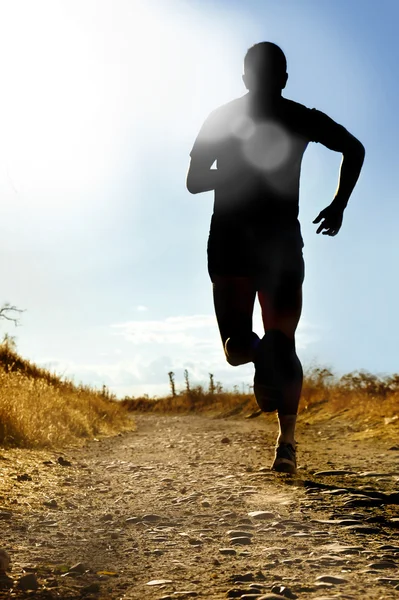 Silhueta de corpo inteiro de extremo cross country homem correndo em pista rural jogging ao pôr do sol — Fotografia de Stock