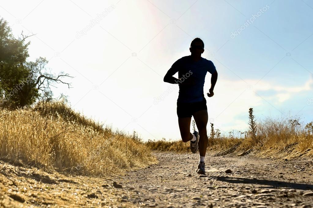 front silhouette young sport man running cross country workout at summer sunset