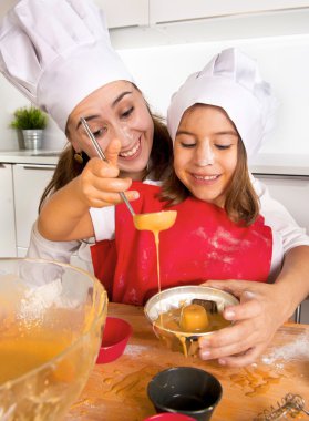 kalıp kek çikolatalı hamur ile doldurma önlük ve aşçı şapkalı küçük kızı ile pişirme anne