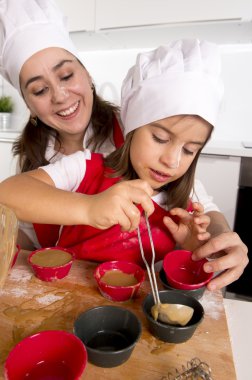 kalıp kek çikolatalı hamur ile doldurma önlük ve aşçı şapkalı küçük kızı ile pişirme anne