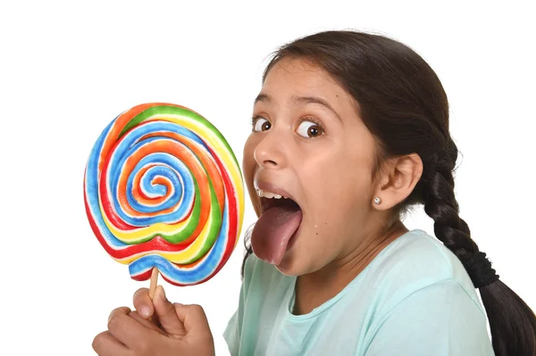 Happy female child holding big lollipop candy licking the candy with her tongue in sugar addiction — Stock fotografie