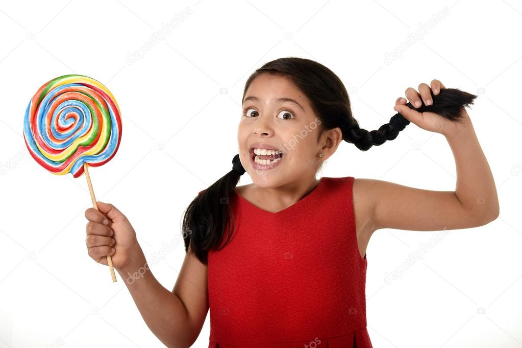 happy female child holding big lollipop candy pulling pony tail with crazy funny face expression in sugar addiction