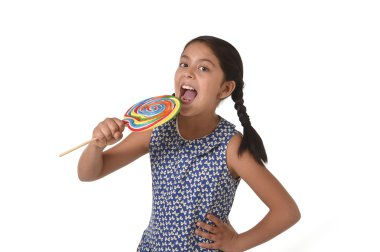 happy female child holding big lollipop candy licking the candy with her tongue in sugar addiction