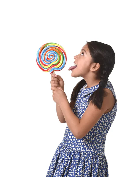 Happy female child holding big lollipop candy licking the candy with her tongue in sugar addiction — Stock fotografie