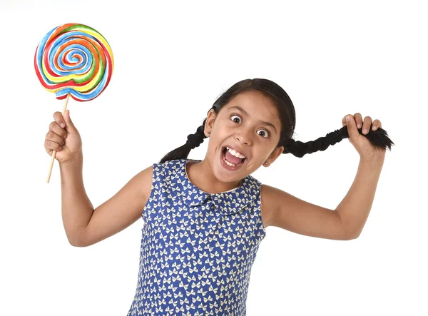 Happy female child holding big lollipop candy pulling pony tail with crazy funny face expression in sugar addiction — 图库照片