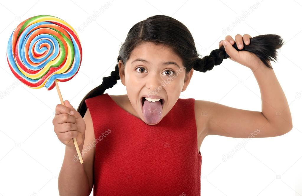 Happy female child holding big lollipop candy pulling pony tail with crazy funny face expression