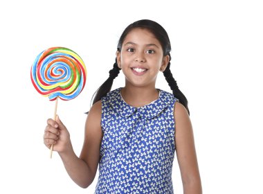 Latin female child holding huge lollipop happy and excited in cute blue dress and pony tails candy concept