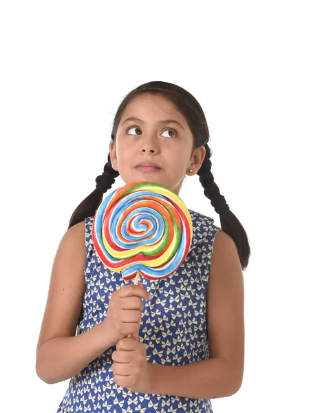 Latina niña sosteniendo enorme piruleta feliz y emocionado en lindo vestido azul y cola de caballo caramelo concepto —  Fotos de Stock