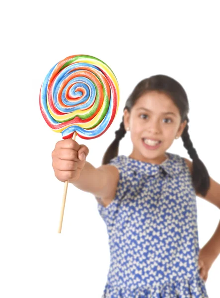 Latin female child holding huge lollipop happy and excited in cute blue dress and pony tails candy concept — Stock fotografie