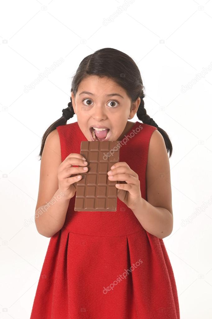 happy female girl in red dress holding with both hands big chocolate eating in happy excited face expression in sugary nutrition