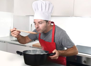 young attractive man in chef hat and red cook apron testing flav