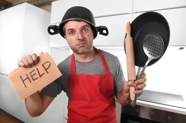 funny man holding pan with pot on head in apron at kitchen askin