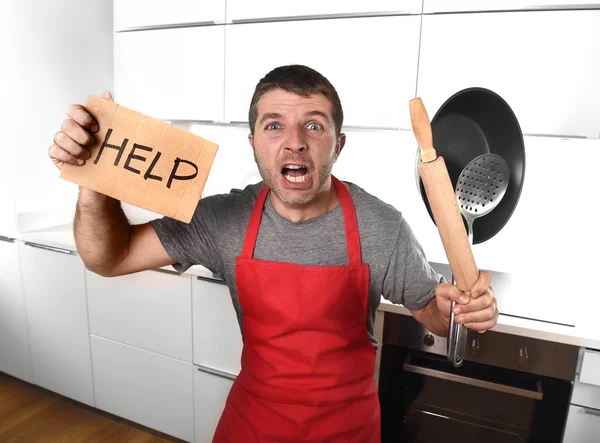 Funny scared man holding pan wearing apron at kitchen asking for — 图库照片