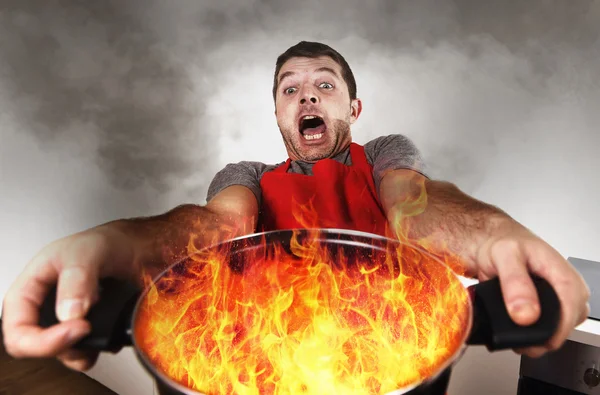 inexperienced home cook with apron holding pot burning in flames