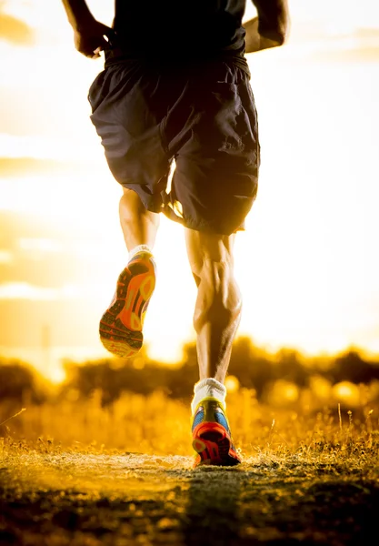 Joven hombre fuerte piernas fuera de pista corriendo en increíble verano puesta de sol en el deporte y estilo de vida saludable —  Fotos de Stock