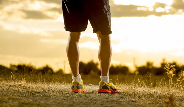 Joven hombre fuerte piernas fuera de pista corriendo en increíble verano puesta de sol en el deporte y estilo de vida saludable — Foto de Stock
