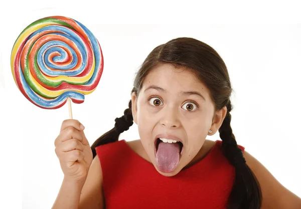 Doce bela latina fêmea criança segurando grande pirulito doce comer e lambendo feliz e animado — Fotografia de Stock