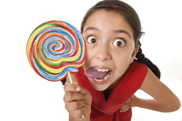 Sugar addict latin female child holding big lollipop candy eating and licking happy crazy excited — Stok fotoğraf