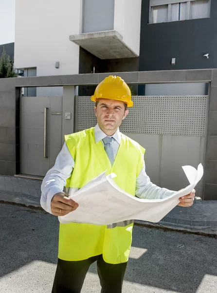 Young attractive foreman worker supervising building blueprints outdoors wearing construction helmet — Zdjęcie stockowe