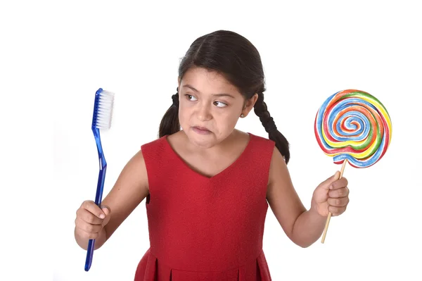Cute female child holding big spiral lollipop candy and huge toothbrush in dental care and health concept — Stockfoto