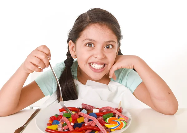 Niña comiendo plato lleno de caramelos en exceso de azúcar y dulce abuso nutricional — Foto de Stock