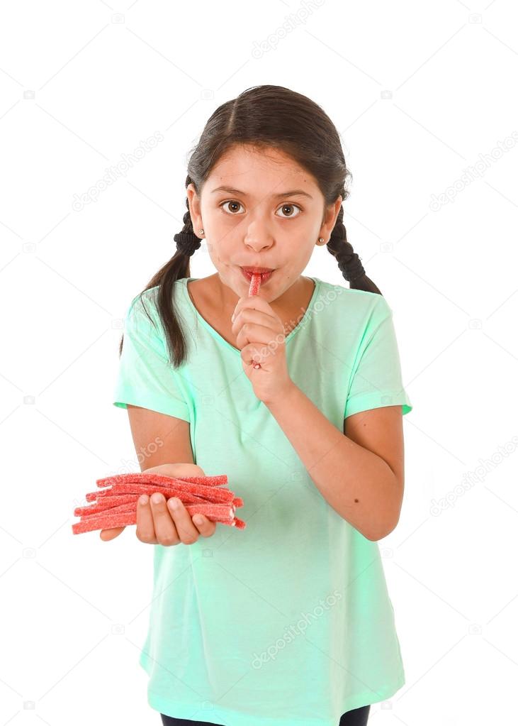 happy cute female child licking and eating red licorice candy in kid love sweet and sugar concept