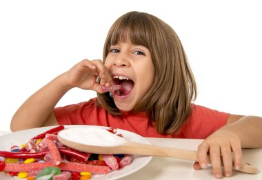 4 or 5 years old child girl eating big multicolor spiral lollipop candy isolated on white background in children love sweet