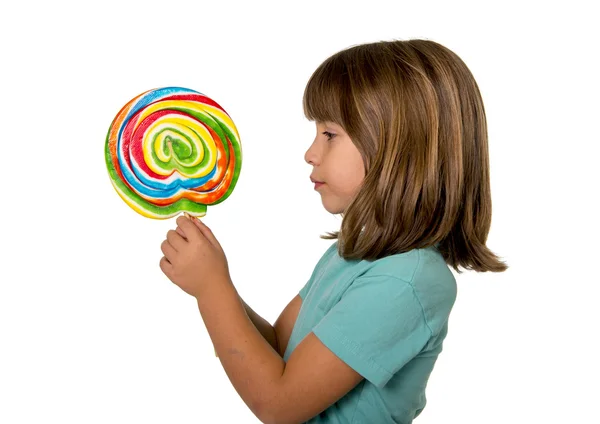 4 or 5 years old child girl eating big multicolor spiral lollipop candy isolated on white background in children love sweet — Stok fotoğraf