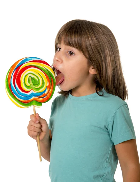 4 ou 5 anos de idade menina comendo e lambendo com a língua grande espiral multicolor pirulito doce — Fotografia de Stock