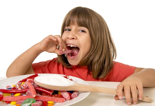 4 or 5 years old child girl eating big multicolor spiral lollipop candy isolated on white background in children love sweet Εικόνα Αρχείου